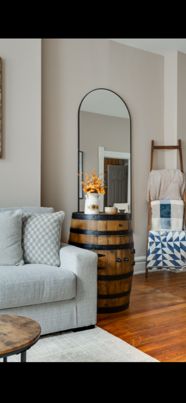 Whiskey barrel accent table styled in a modern living room with mirror and autumn florals