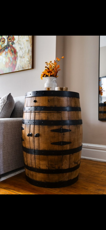 Full whiskey barrel repurposed as a living room accent table with autumn floral arrangement