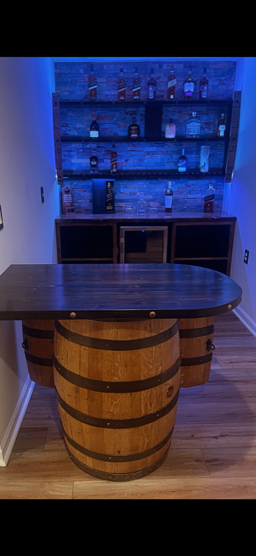 Custom barrel bar with LED-lit reclaimed wood shelving displaying premium spirits