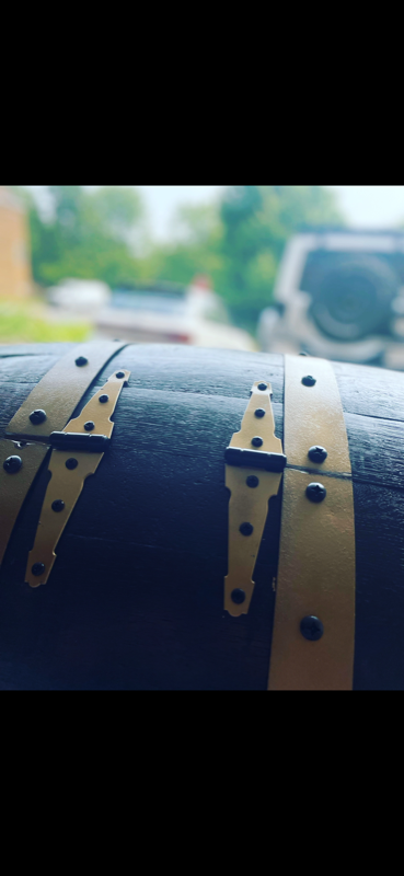 Close-up detail of polished brass bands and decorative hardware on a custom painted barrel